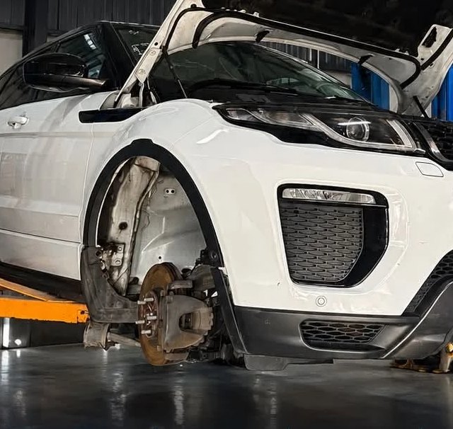 A Range Rover Evoque raised on the two-post lift with a wheel off, part-way through mechanical work.