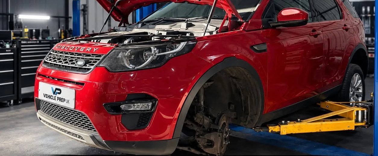 A Land Rover Discovery Sport on the ramp with the bonnet up during a service.